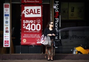 Woman holds shopping bags as she stands outside a store on a main street in Sydney